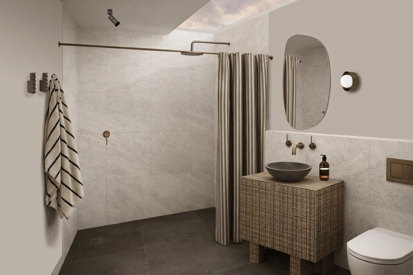 Studio bathroom with a stone basin on a woven vanity, antique brass tapware and a striped shower curtain